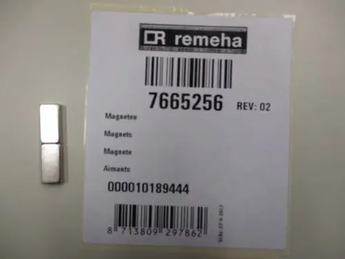 Magneten von Remeha auf einer Etikette, die die Artikelnummer 7665256 zeigt. Neben dem Etikett liegt ein magnetischer Bauteil in einer einfachen Form.